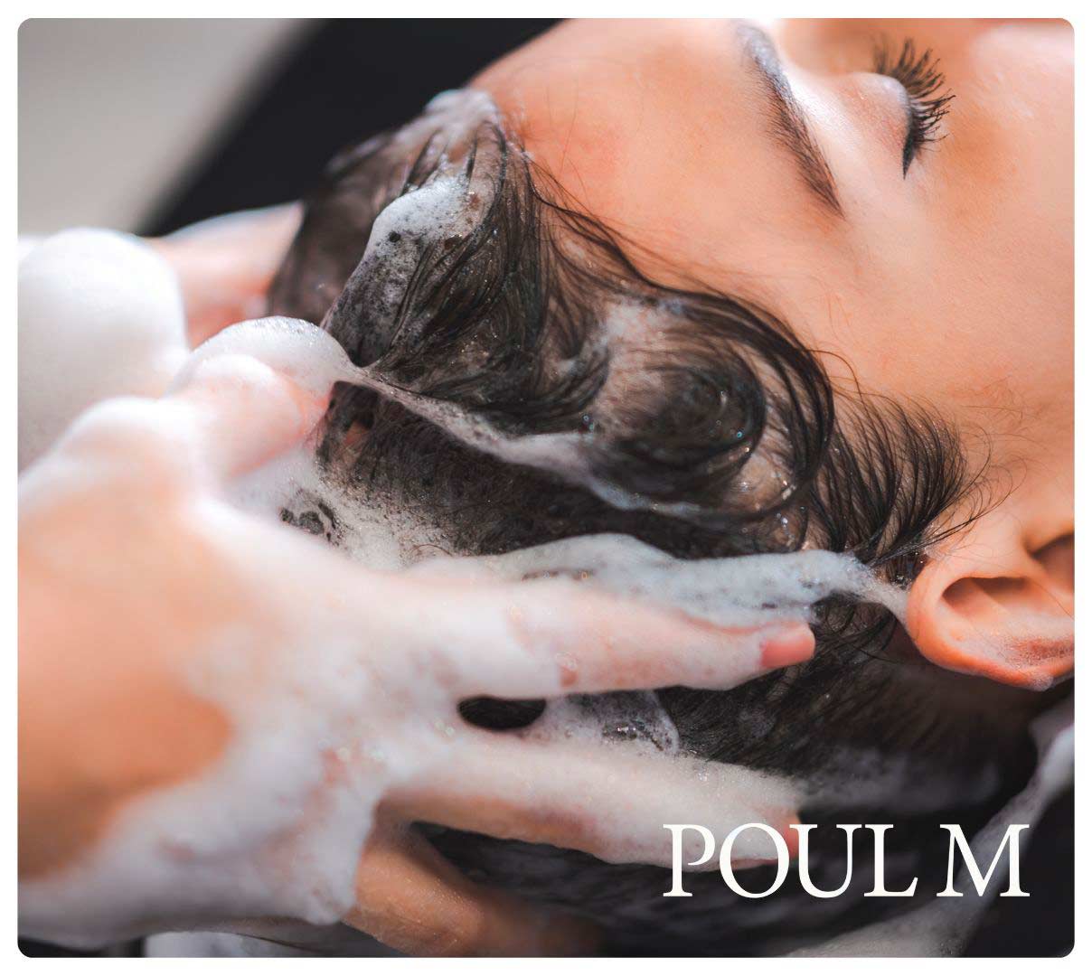 kvinde sidder i frisørstolen ved vasken og får vasket hår med hårshampoo